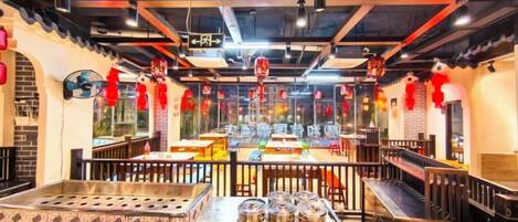 Un interior de restaurante con zona de comedor central, cabinas y una barra.