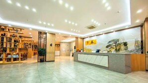 A spacious lobby with a reception desk, bookshelves, and a large mural. - Danzhou Guanlan Shangpin International Hotel (Danzhou)
