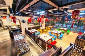 A restaurant with multiple tables and chairs, a counter with a display case, and a view through the window. - Danzhou Guanlan Shangpin International Hotel (Danzhou)