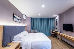 A hotel room with a bed, a desk, a chair, a TV, and a window with curtains. - Danzhou Guanlan Shangpin International Hotel (Danzhou)