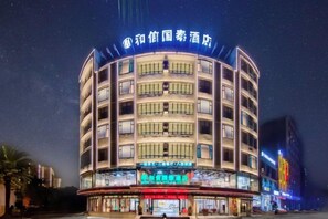 Un hotel de varios pisos con fachada curva, señalización iluminada y una entrada destacada.