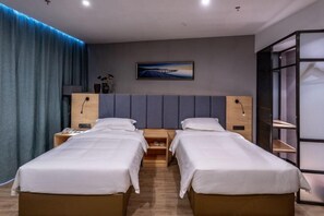 A hotel room with two single beds, a wooden headboard, a nightstand with a phone, a painting on the wall, and a large window with curtains. - Danzhou Guanlan Shangpin International Hotel (Danzhou)