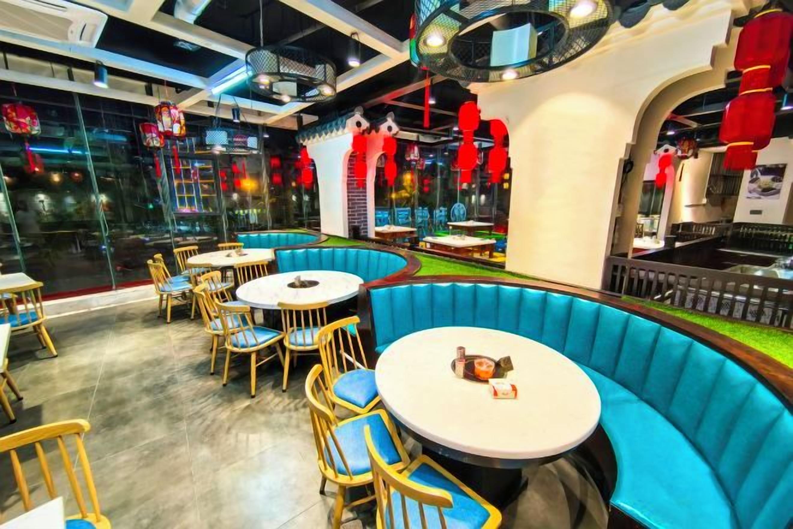 A restaurant with round tables and blue booths, featuring a modern interior design.
