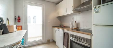 Una cocina con estufa, horno, pileta y ventana.