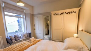 A neatly arranged bedroom with a large bed, a wardrobe, and a window with a view. - Yewbarrow Cottage (Grange-over-Sands)