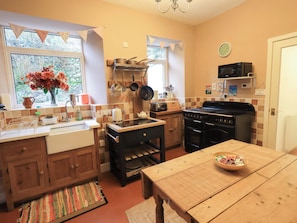A compact kitchen with wooden cabinets, a stove, and a small dining table.