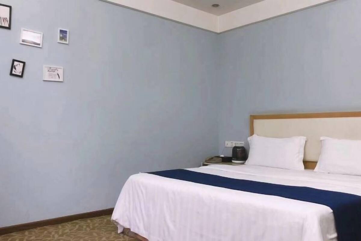 A hotel room with a bed, a nightstand, and a wall with framed pictures.