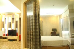 Een hotelkamer met een bed, een bureau met een computer, een televisie en een raam met gordijnen.