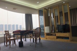 Una sala de estar amplia con un gran ventanal, un televisor de pantalla plana y un comedor con sillas y una mesa.