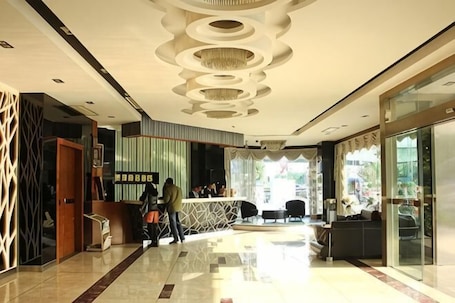A hotel lobby with a reception desk, seating area, and a glass entrance.. Xiaolan Yinhe Business Hotel