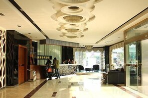 Vestíbulo de hotel con recepción, zona de estar y entrada de vidrio.