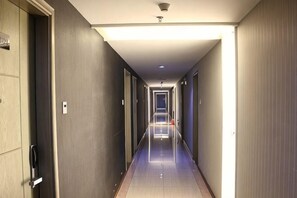 A long, narrow hotel corridor with doors on both sides, a ceiling light, and a visible door at the end. - Xiaolan Yinhe Business Hotel (Zhongshan)