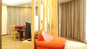 A hotel room with a seating area, a television, and curtains. - Xiaolan Yinhe Business Hotel (Zhongshan)