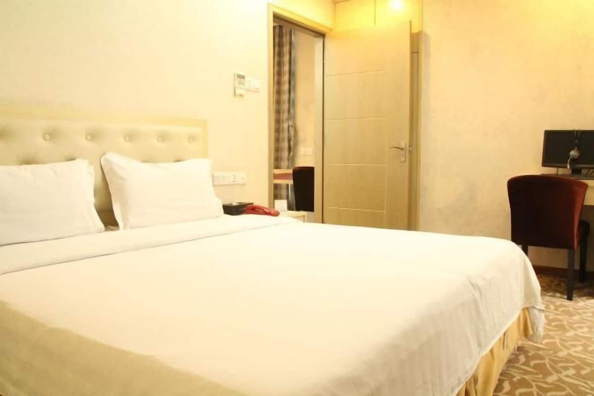 A hotel room with a large bed, a desk, and a chair.