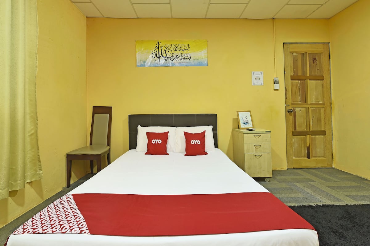 Une chambre d’hôtel avec un lit, une table de chevet, une chaise et une porte.