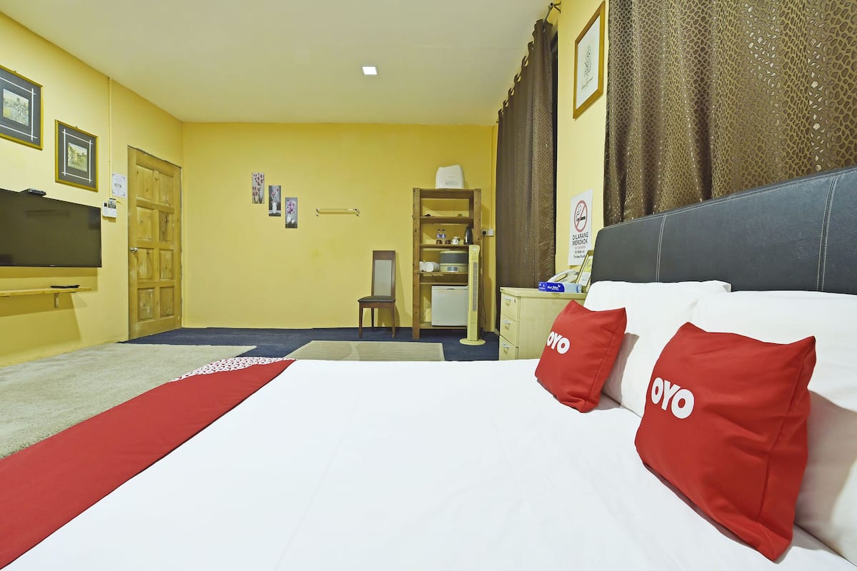 Une chambre d’hôtel équipée d’un lit, d’un bureau, d’une chaise, d’une télévision et d’une étagère contenant des articles de toilette.