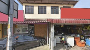 A building with a storefront, a parked car, and a motorcycle. - OYO 90535 Wakaf Bharu Inn (Tumpat)