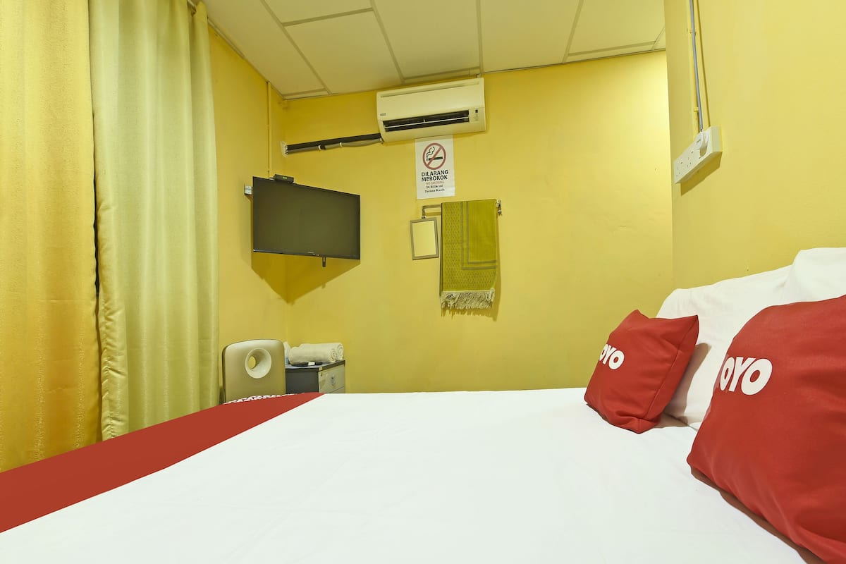 Une chambre d’hôtel équipée d’un lit, d’une télévision, d’un système de climatisation et d’un panneau indiquant qu’il est interdit de fumer.