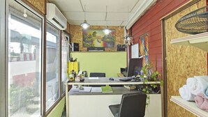 A small office with a desk, chair, computer, and various office supplies. There is a window with a view of the outside, and a painting on the wall. - OYO 90535 Wakaf Bharu Inn (Tumpat)