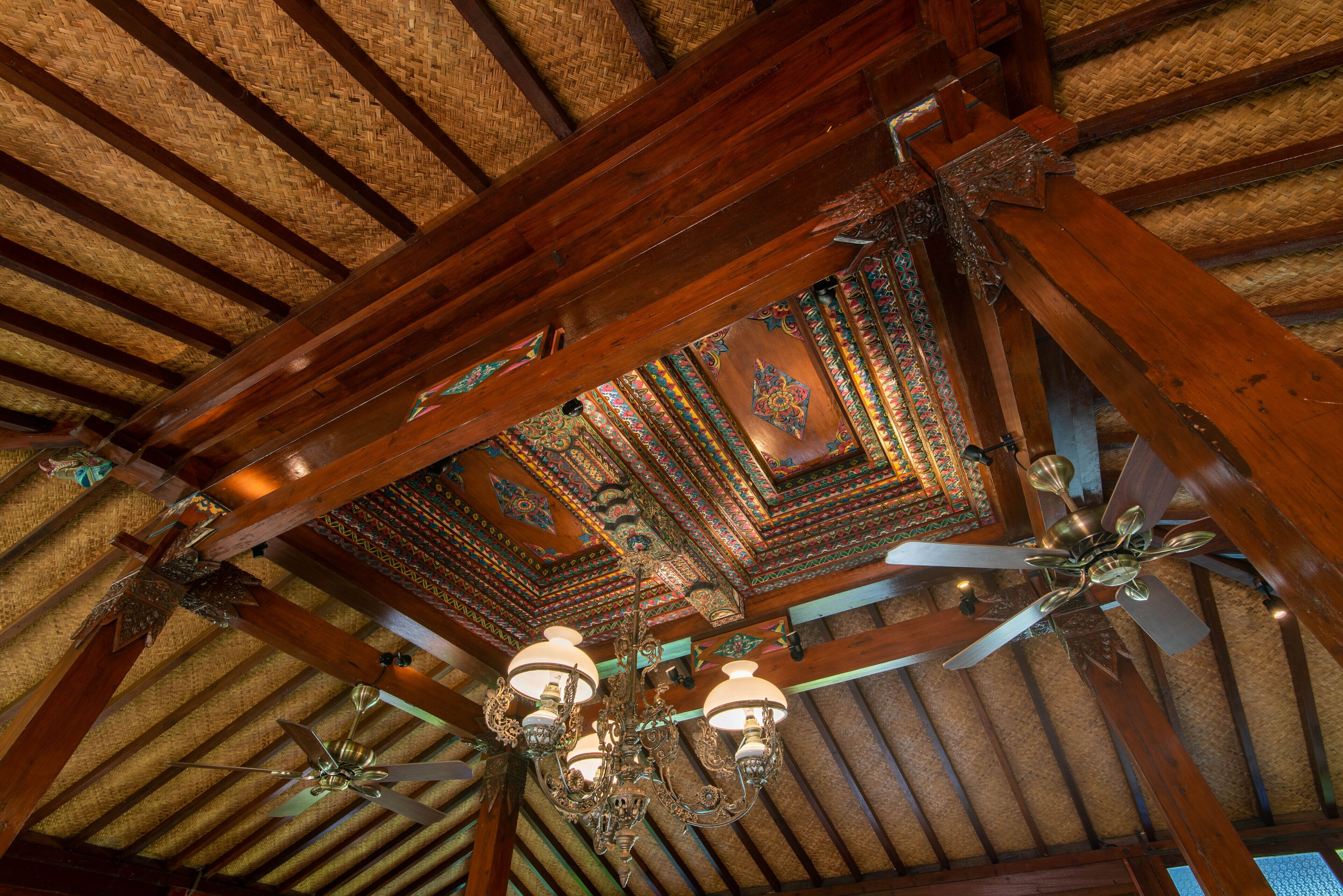 A wooden ceiling with a decorative pattern and a ceiling fan.