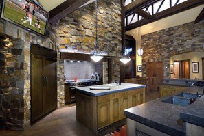 Una cocina con paredes de piedra, armarios de madera y una isla grande con un fregadero.