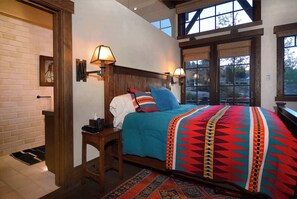 Un dormitorio con cama, lámparas de noche, cabecero de madera y vistas por la ventana.
