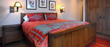 Un dormitorio con cama de madera, dos lámparas de pared, una mesita de noche y un armario.