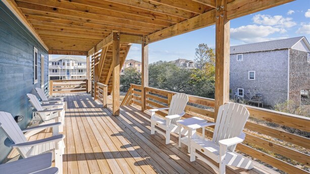 A wooden deck with white Adirondack chairs and tables, overlooking a residential area. - 1486 - Blue Retreat - Whalehead Corolla Escape w/ Pool & Hot Tub (Corolla)