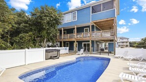 A two-story building with a swimming pool and outdoor seating. - 1486 - Blue Retreat - Whalehead Corolla Escape w/ Pool & Hot Tub (Corolla)