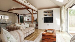 A cozy living room with a sofa set, wooden coffee table, and a bookshelf. - Oast Cottage (Maidstone)