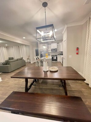 A modern kitchen with white cabinets, a dining table, and a bench.