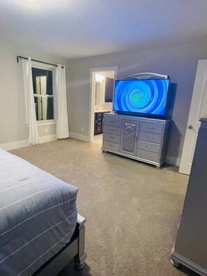 A bedroom with a bed, a dresser, and a television on a stand.
