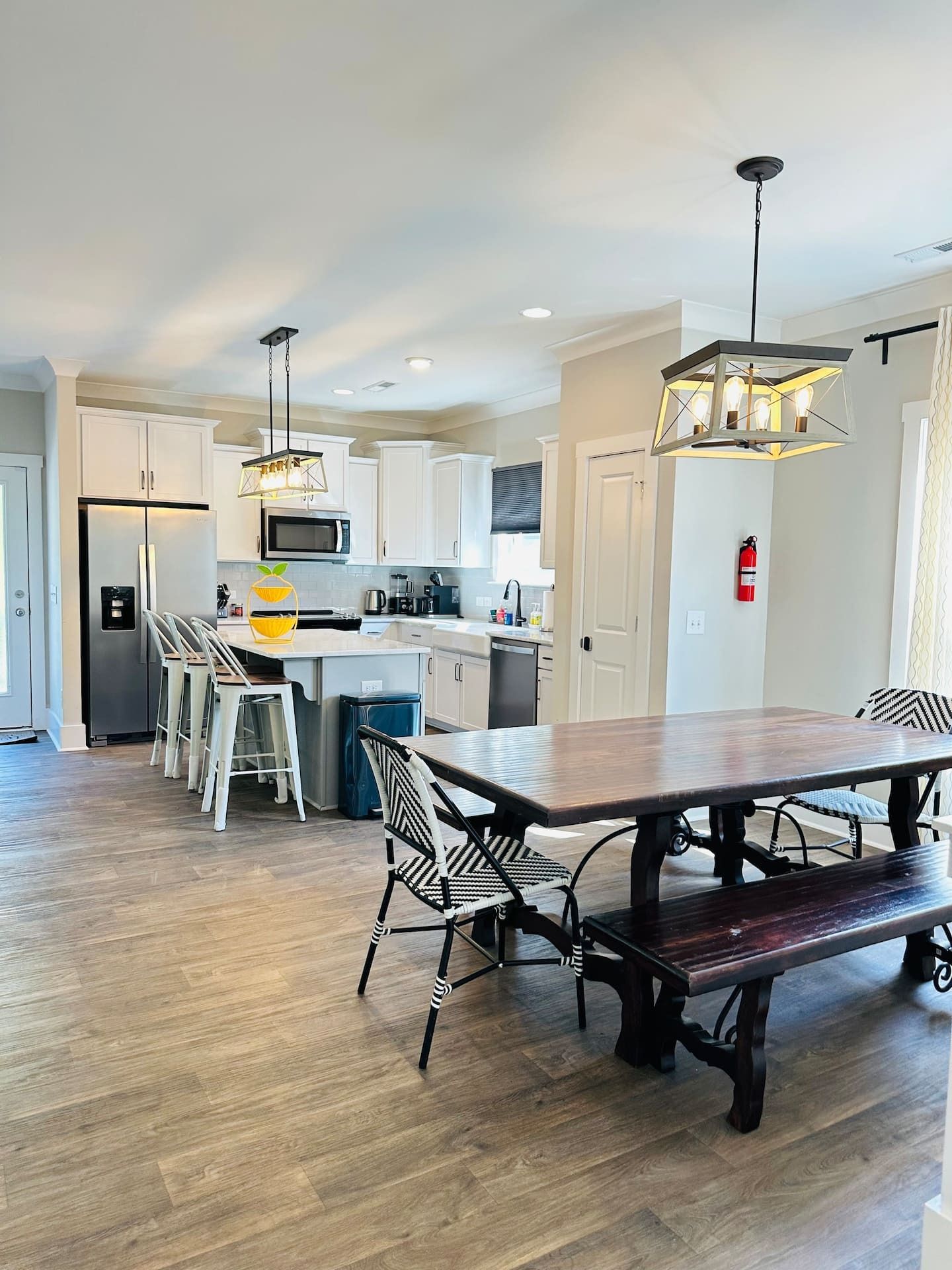 A modern kitchen with white cabinets, stainless steel appliances, and a dining area with a wooden table and chairs.
