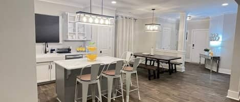 A modern kitchen with a central island, bar stools, and pendant lighting.
