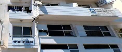 A multi-story building with signage for 'MISHELLIS COURT' and 'NICUS MAJORUM ASSOCIATES'.