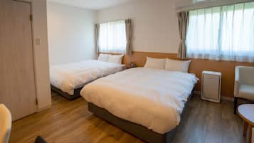 A hotel room with two beds, a chair, a table, and an air conditioning unit.