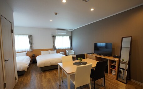 A hotel room with a bed, a desk with a chair, a television, and a small table with a plant.