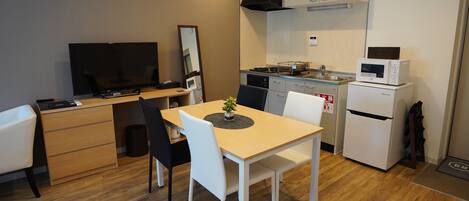 Une cuisine compacte comprenant une table à manger, des chaises, un téléviseur, un four à micro-ondes et un réfrigérateur.