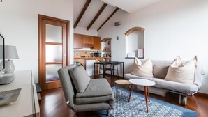 A compact living space with a kitchenette, a sofa with cushions, a patterned armchair, a small dining table, and a lamp. - Italianway - Costiglioli 8 B (Sanremo)