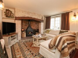 Una sala de estar acogedora con chimenea de piedra, televisor, sofá y alfombra estampada.