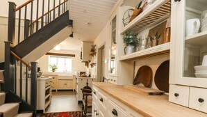 Una cocina con escalera de madera, armarios blancos y una alfombra roja estampada.