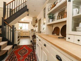 Una cocina con escalera de madera, armarios blancos y una alfombra roja estampada.