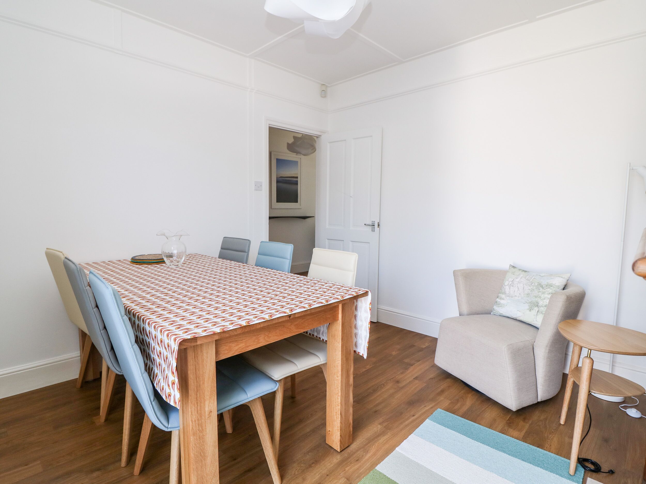 A dining area with a wooden table and chairs, a sofa, and a small side table.