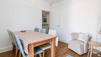 A dining area with a wooden table and chairs, a sofa, and a small side table.