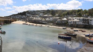 A coastal town with a sandy beach, boats, and houses along the shore.