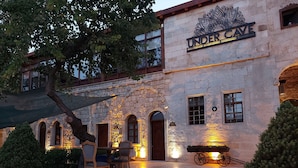 Un edificio de piedra con un letrero que dice "UNDERCAVE" y un área de estar al aire libre rústica con una mesa y sillas.