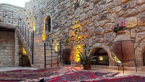 Un patio con muros de piedra, un letrero de restaurante y alfombras tradicionales.
