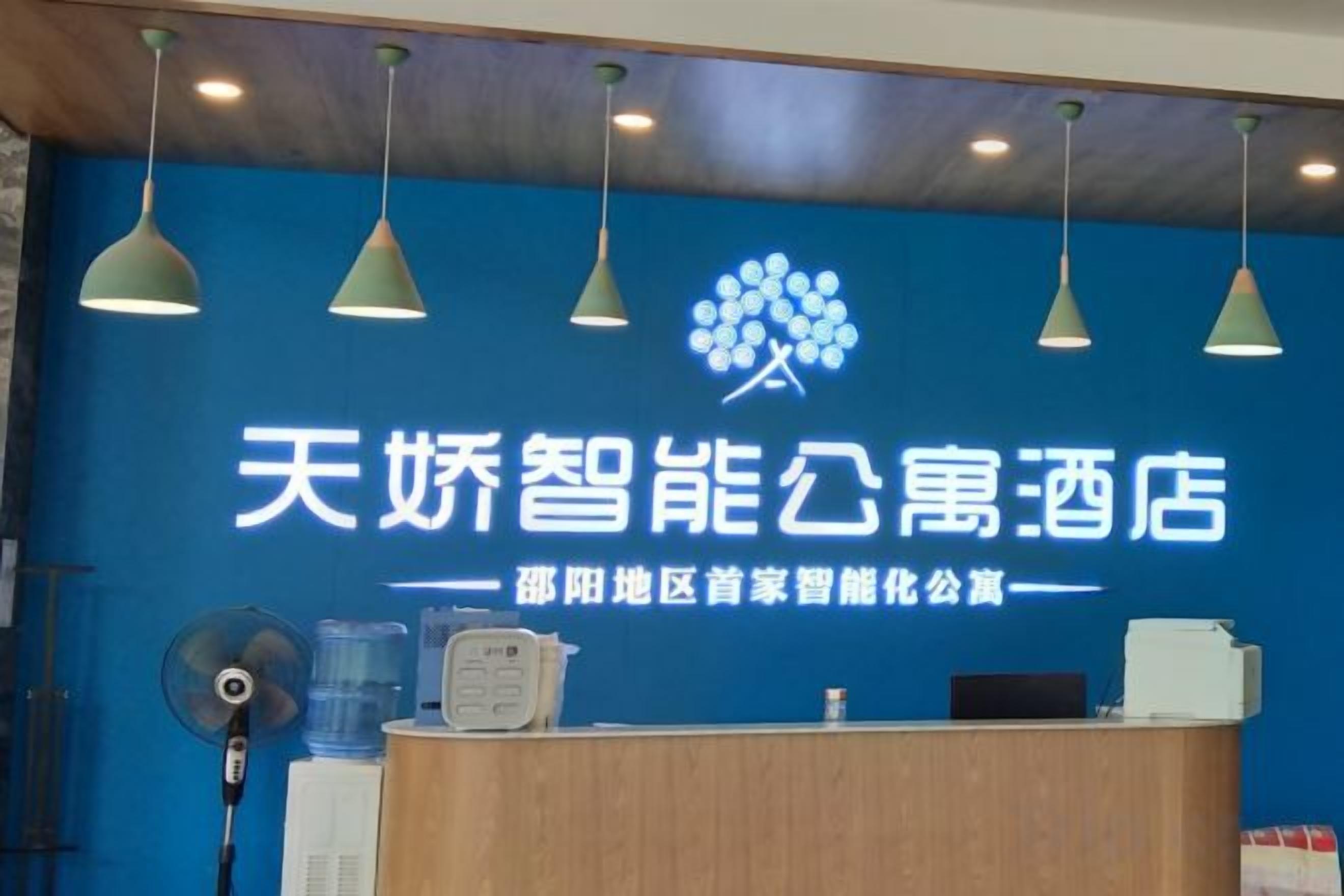 Una reception con parete azzurra, un logo, una ventola e un dispenser d'acqua.