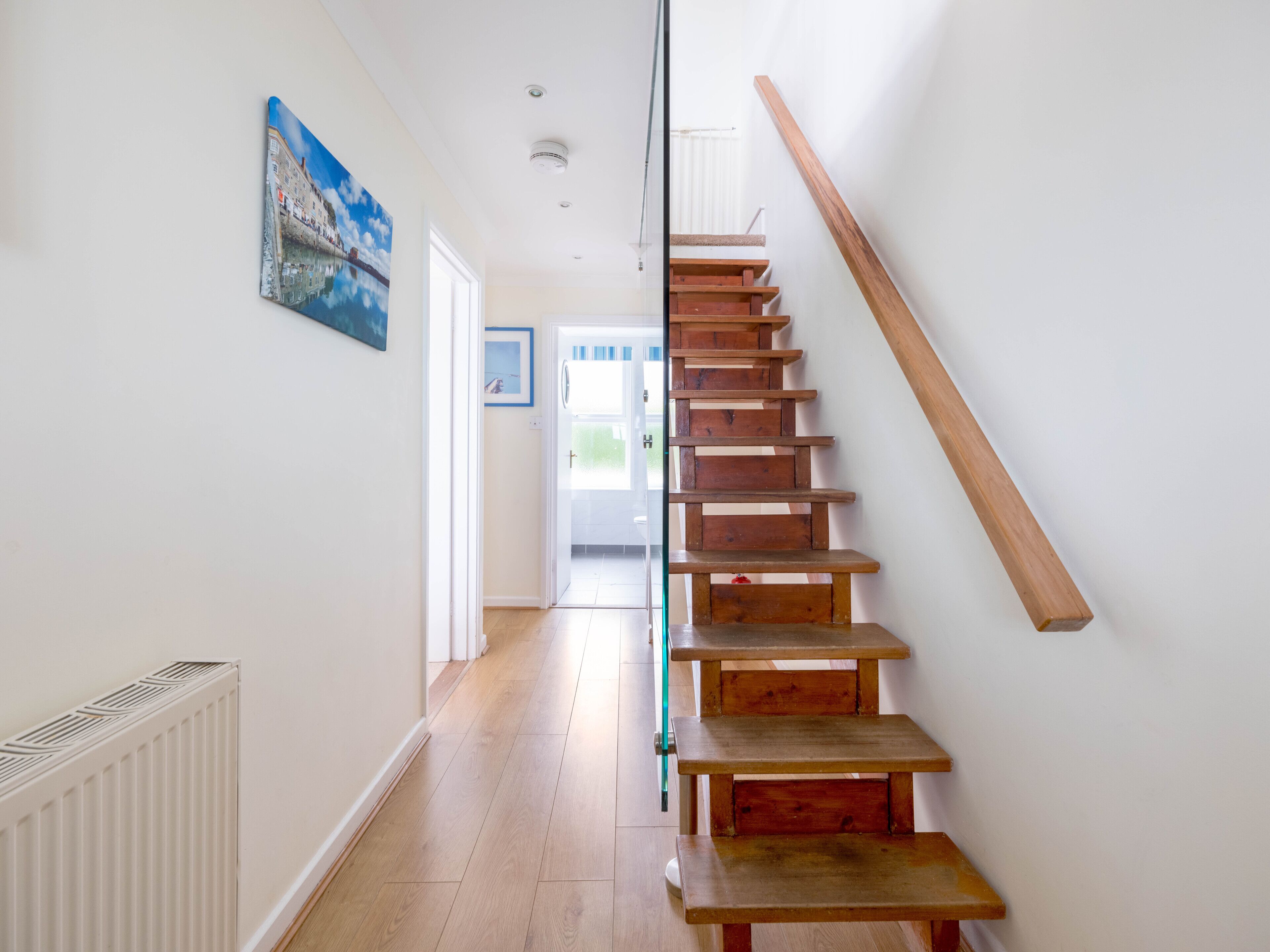 A wooden staircase with a glass door leading to a bright room.