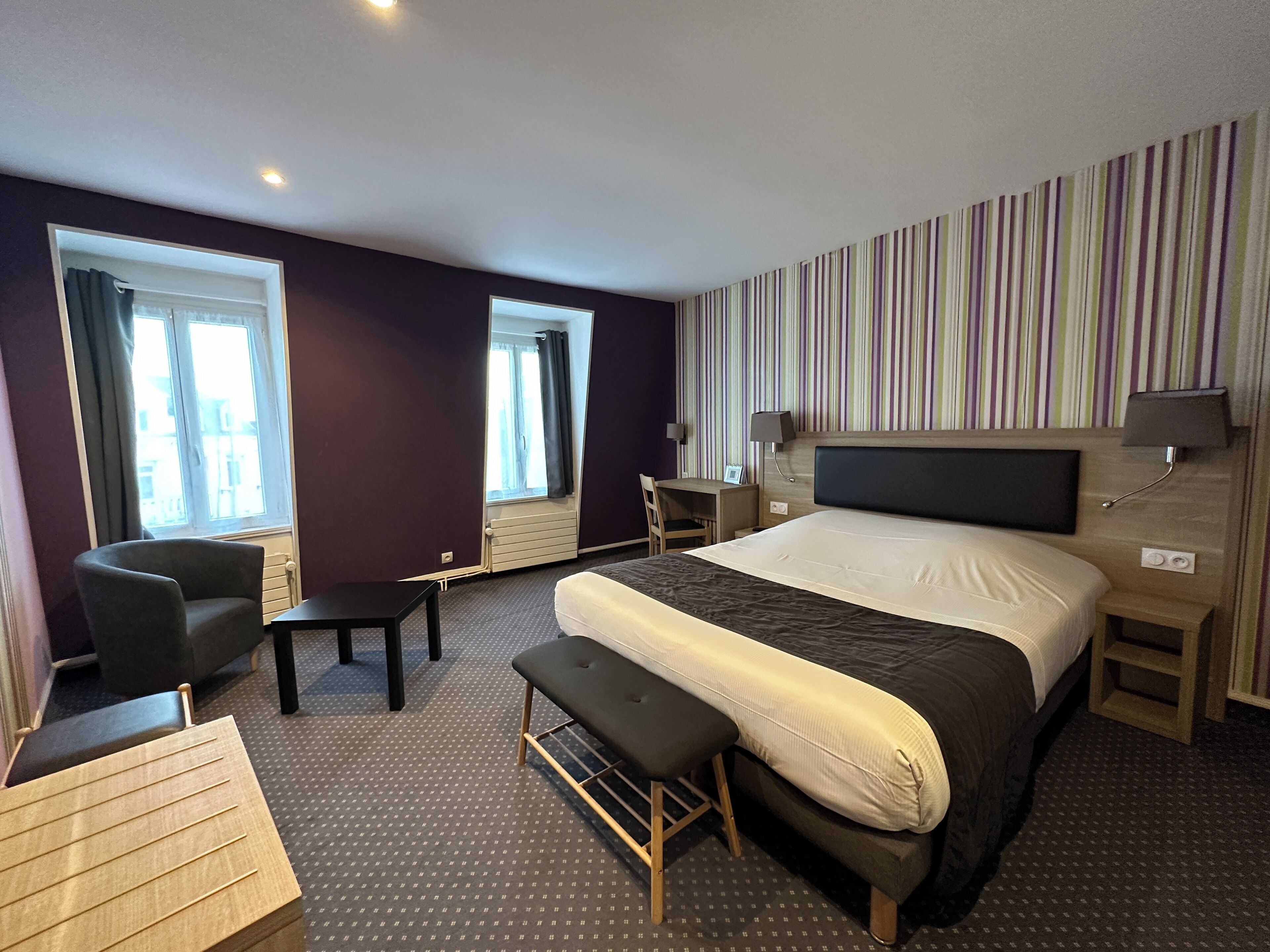 Une chambre d’hôtel avec un grand lit, un bureau, une chaise et un banc.